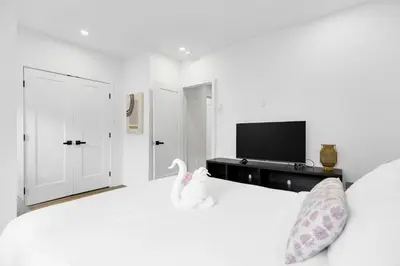 a white bedroom with a white bed and a tv at Boutique 4BR Luxury Residence 2 Floors Mile-End St-Laurent in Montréal