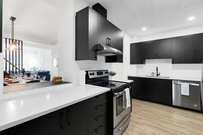 a kitchen with black cabinets and white counter tops at Boutique 4BR Luxury Residence 2 Floors Mile-End St-Laurent in Montréal