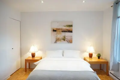 a bedroom with a large white bed with two lamps at updated and cozy 2 bedroom unit, fully furnished, downtown, 32 days minimum in Montréal