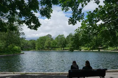 two people sitting on a bench in front of a lake at updated and cozy 2 bedroom unit, fully furnished, downtown, 32 days minimum in Montréal
