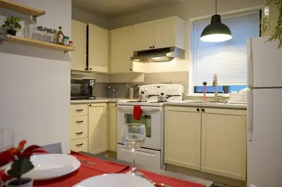 a kitchen with white appliances and a table with a wine glass at updated and cozy 2 bedroom unit, fully furnished, downtown, 32 days minimum in Montréal