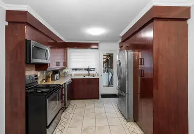 a kitchen with wooden cabinets and stainless steel appliances at COSY 3 BEDROOMS Montreal in Montréal