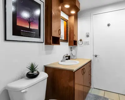 a bathroom with a toilet and a sink with a picture on the wall at COSY 3 BEDROOMS Montreal in Montréal
