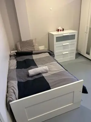 a white bedroom with a bed and a dresser at La maison internationale de Montréal in Montréal