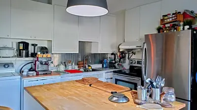 a kitchen with white cabinets and a wooden counter top at Urbanity et cosy in Montréal