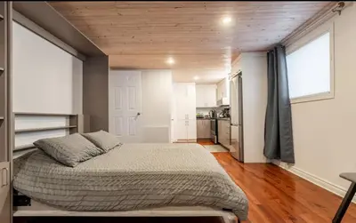 a bedroom with a large bed and a kitchen at Le Loft in North Hatley