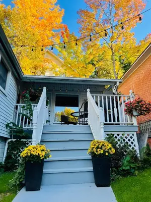 a house with a porch with stairs and flowers at Le Loft in North Hatley