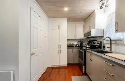 a white kitchen with white cabinets and a sink at Le Loft in North Hatley