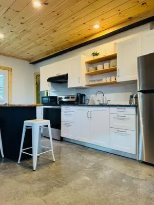 a kitchen with white cabinets and a stool in it at Le Garage 17 in Frelighsburg