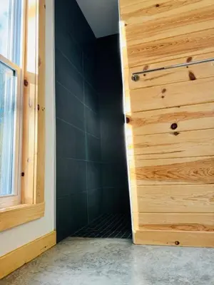 a bathroom with a wooden door and a window at Le Garage 17 in Frelighsburg