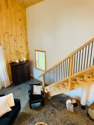 a living room with a staircase and a chair at Le Garage 17 in Frelighsburg
