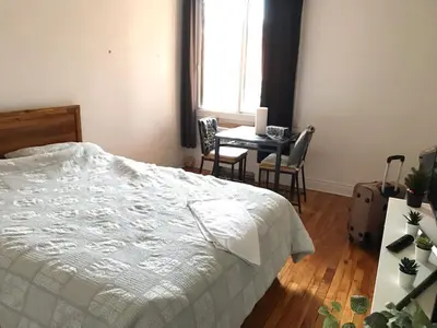 a bedroom with a bed and a table and chairs at Chambre spacieuse in Montréal