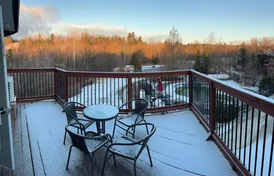 a balcony with a table and chairs on a snow covered deck at Condos hotel lion d or in Magog-Orford
