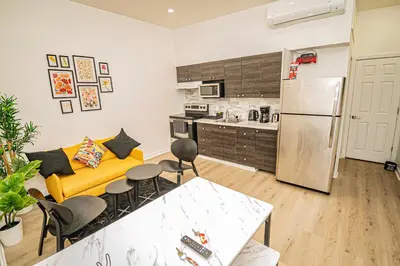 a living room with a yellow couch and a kitchen at Three bedroom chic condo downtown Montreal in Montréal