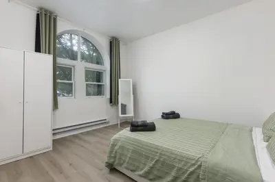 a white bedroom with a bed and a large window at Three bedroom chic condo downtown Montreal in Montréal