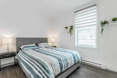 a white bedroom with a bed and a window at Huge 3 Bedroom Condo with a Large Patio in Montréal