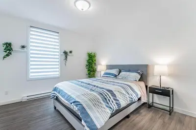 a white bedroom with a bed and a window at Huge 3 Bedroom Condo with a Large Patio in Montréal