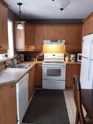 a kitchen with white appliances and wooden cabinets at Villa le Voyageur in Sherbrooke