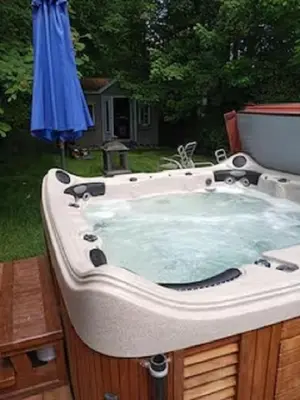 a bath tub in a yard with a blue umbrella at Villa le Voyageur in Sherbrooke