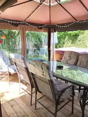 a glass table and chairs under an umbrella on a patio at Villa le Voyageur in Sherbrooke