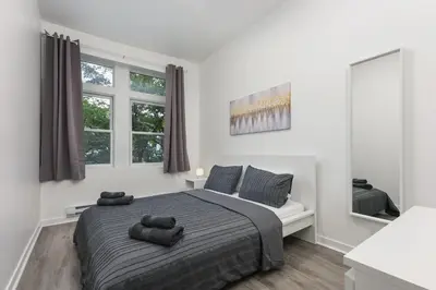 a white bedroom with a bed and two windows at Brand new 2 bedroom in the heart of the city in Montréal