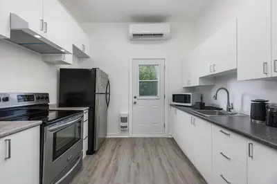 a kitchen with white cabinets and stainless steel appliances at Brand new 2 bedroom in the heart of the city in Montréal