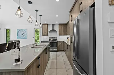 a kitchen with a stainless steel refrigerator and wooden cabinets at Chalet Le PÜR in Eastman