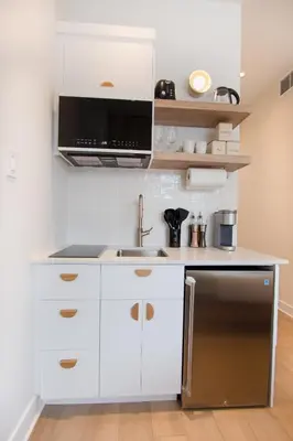 a kitchen with white cabinets and a stainless steel refrigerator at Studio #3 - Self Check-In - Plateau - St-Denis in Montréal