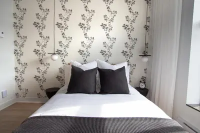 a bedroom with a bed with white sheets and floral wallpaper at Studio #4 - Self Check-In - Plateau - St-Denis in Montréal