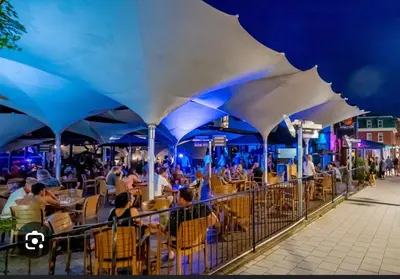 a group of people sitting at tables under blue umbrellas at Escape Mont Orford in Magog-Orford