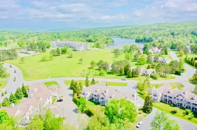 an aerial view of a house with a park and a lake at Escape Mont Orford in Magog-Orford