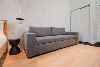 a gray couch in a room with a bed at Studio #11 - Self Check-In - Plateau - St-Denis in Montréal