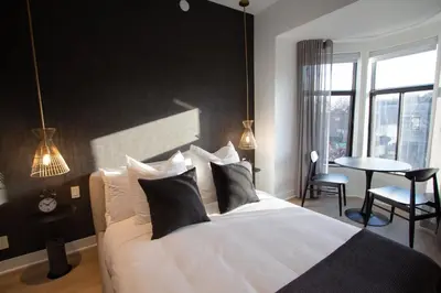 a bedroom with a white bed with black walls and a table at Studio #13 - Self Check-In - Plateau - St-Denis in Montréal