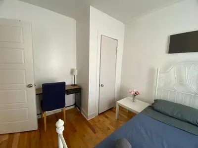 a bedroom with a bed and a desk and a door at Chambre supérieure, ensoleillée et spacieuse in Montréal
