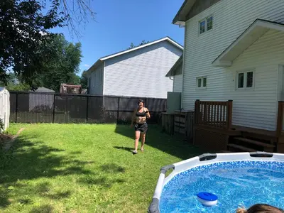 a woman standing in a yard next to a pool at La Maison 4 Saisons, chambre-Hiver in Saint-Jean-sur-Richelieu