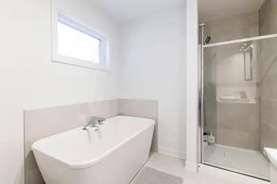 a white bathroom with a tub and a shower at T3 10 mins to La Ronde nice , Cozy 3 bedroom longueuil in Longueuil