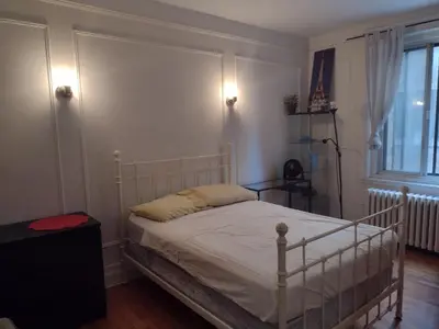a bedroom with a white bed and a window at Antic Style with high ceiling in Montréal