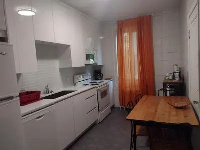 a kitchen with white cabinets and a wooden table at Antic Style with high ceiling in Montréal