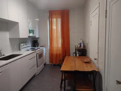 a kitchen with a wooden table and an orange curtain at Antic Style with high ceiling in Montréal