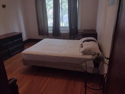 a bedroom with a bed and a table and window at Antic Style with high ceiling in Montréal