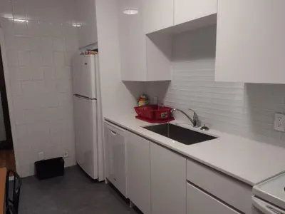 a white kitchen with a sink and a refrigerator at Antic Style with high ceiling in Montréal