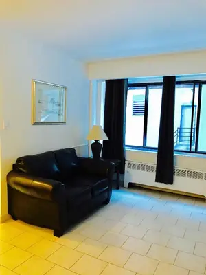 a living room with a black couch and windows at Stylish Montreal Apartment Comfortable Stay in the Golden Square Mile in Montréal