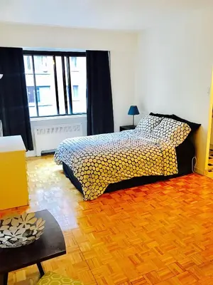 a bedroom with a bed and a wooden floor at Stylish Montreal Apartment Comfortable Stay in the Golden Square Mile in Montréal