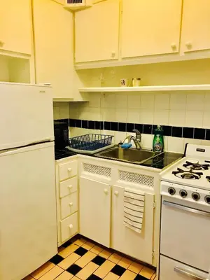 a white kitchen with a sink and a stove at Stylish Montreal Apartment Comfortable Stay in the Golden Square Mile in Montréal