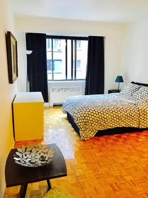a bedroom with a bed and a table with a flower bowl on it at Stylish Montreal Apartment Comfortable Stay in the Golden Square Mile in Montréal