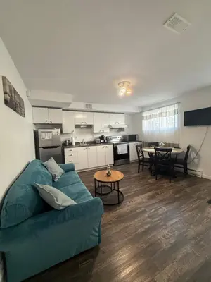 a living room with a blue couch and a kitchen at Charmant appartement au sous-sol in Longueuil