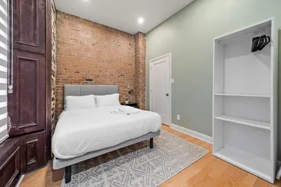 a bedroom with a bed and a brick wall at The Ontario Loft Suites in Montréal