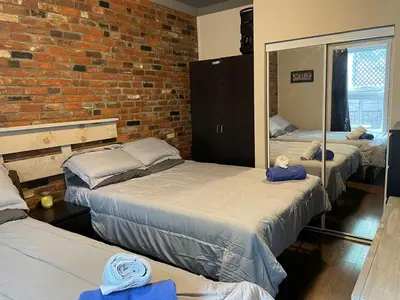 a room with three beds and a brick wall at cozy apartment in the heart of downtown Montreal in Montréal