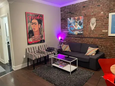 a living room with a couch and a brick wall at cozy apartment in the heart of downtown Montreal in Montréal