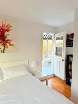 a white bedroom with a bed and a sliding glass door at Cozy & spacious 3 BDR condo in Montréal